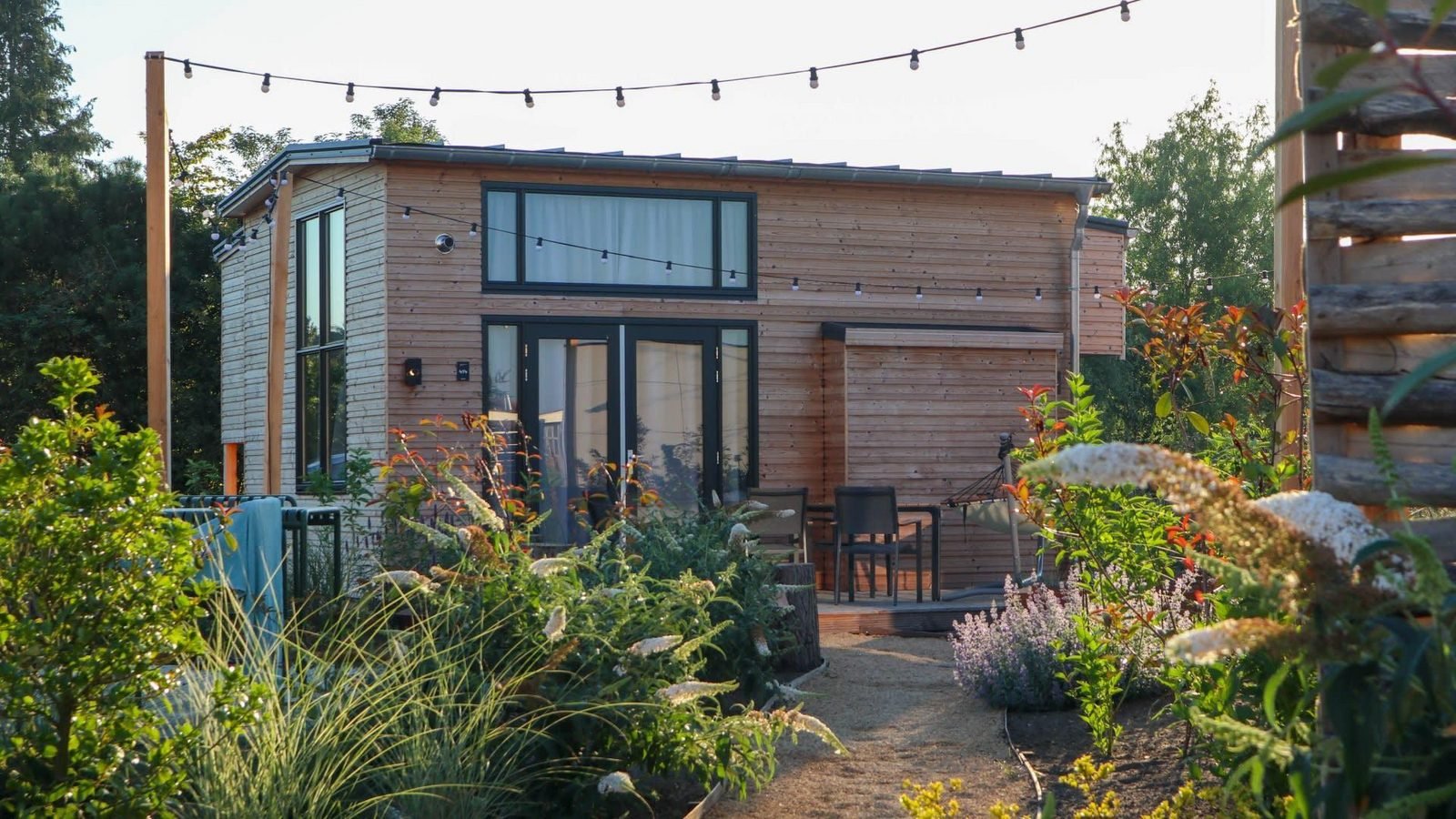 Exterieur van Tiny House 4 aan het water bij Marina Strandbad, met een houten terras en uitzicht op de jachthaven.