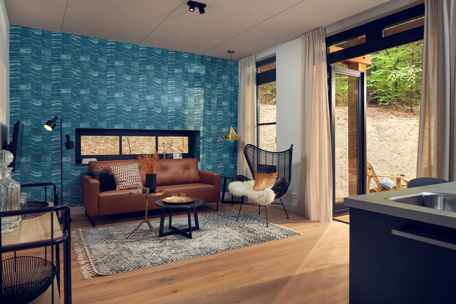Ruime suite met zithoek, houten vloer en grote ramen met uitzicht op het bos van Hotel Beekhuizen in Gelderland.