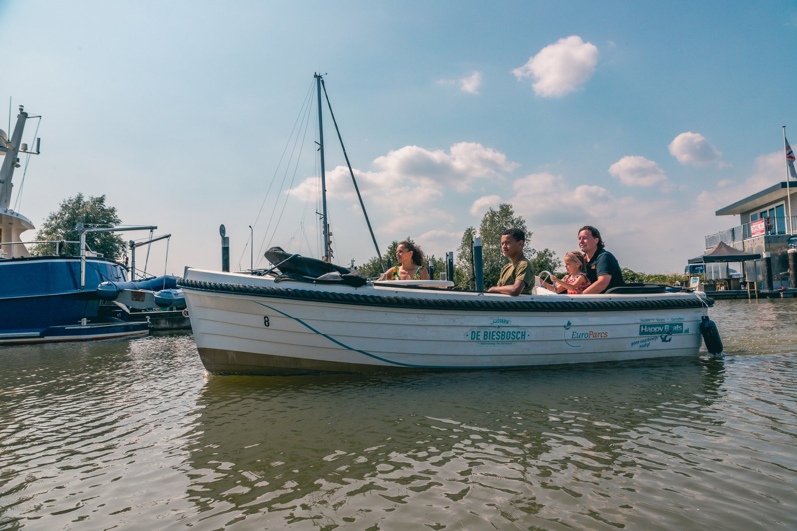 Afbeelding bij EuroParcs De Biesbosch Zicht op de jachthaven van EuroParcs De Biesbosch, omringd door groen en water, met boten aangemeerd.