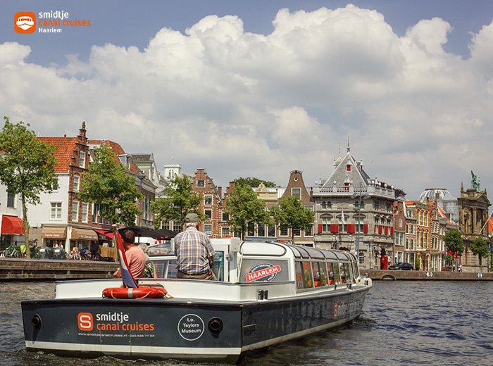 Een rondvaartboot vaart door de grachten van Haarlem, langs historische panden en een ophaalbrug.