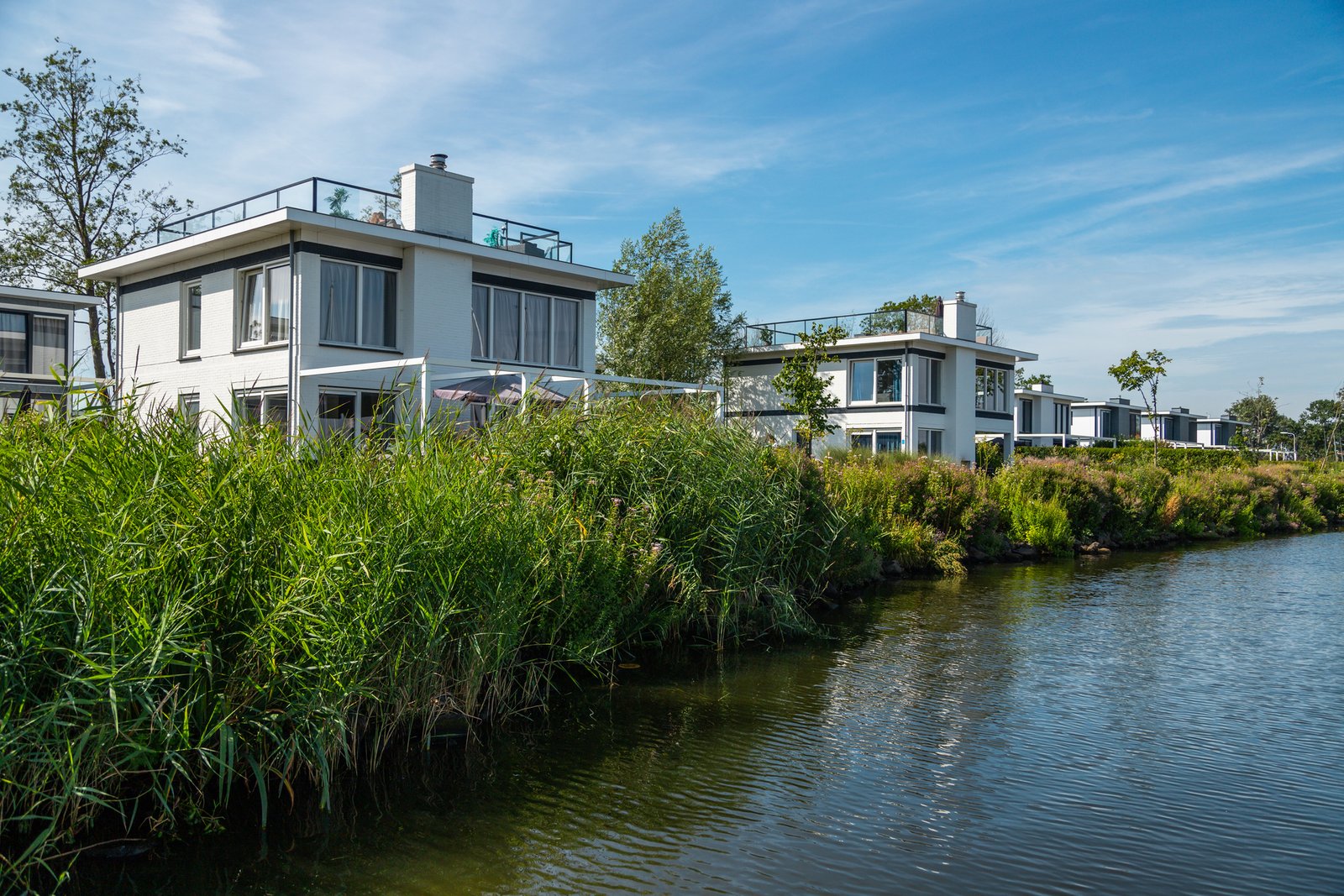 Zicht op het vakantiepark EuroParcs Bad Hulckesteijn met luxe huisjes aan het water van het Nijkerkernauw.