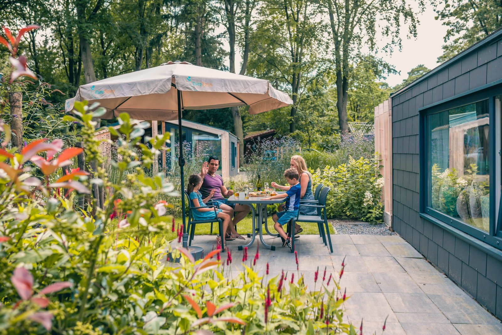 Afbeelding bij EuroParcs Secret Parcs Luxe Family Garden accommodatie van EuroParcs De Utrechtse Heuvelrug, met een ruim terras en uitzicht op het groene park.
