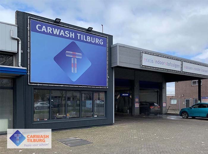 Afbeelding bij Wasbeurt bij Carwash Tilburg Een auto wordt grondig gewassen bij een carwash in Tilburg, met water en schuim op de carrosserie.