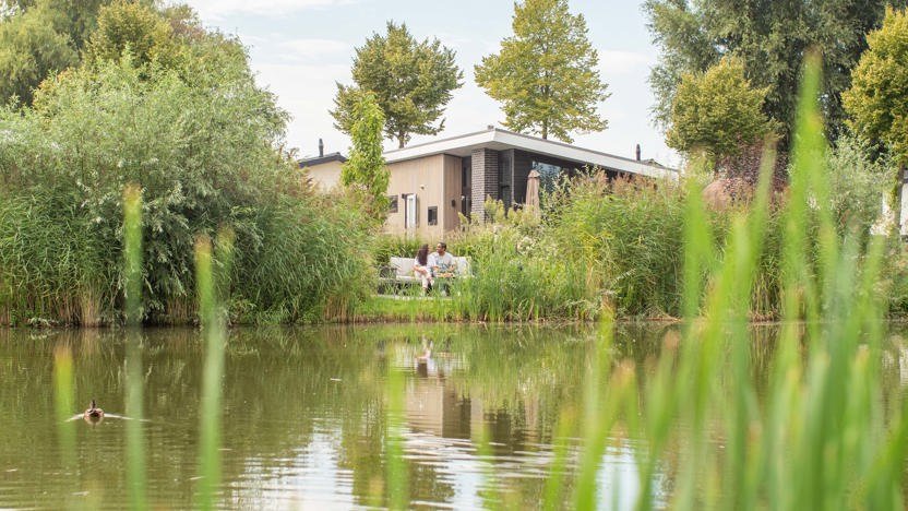 Vakantiegasten zitten ontspannen op het terras van een vakantiewoning op Recreatiepark het Esmeer in Aalst, Gelderland.