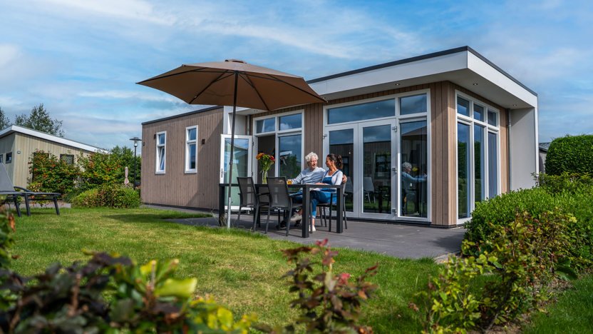 Vakantiegasten ontspannen bij hun woning op Park Westerkogge, omringd door groen in Noord-Holland.